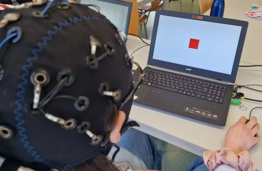 Kabellose EEG-Hauben, wie sie in der aktuellen Studie verwendet wurden, werden am Fachbereich Psychologie der Universität Konstanz auch in der Lehre genutzt. Hier probiert eine Studentin ein klassisches EEG-Experiment (Oddball) aus. (Credits: Karl-Philipp Maria Flösch)