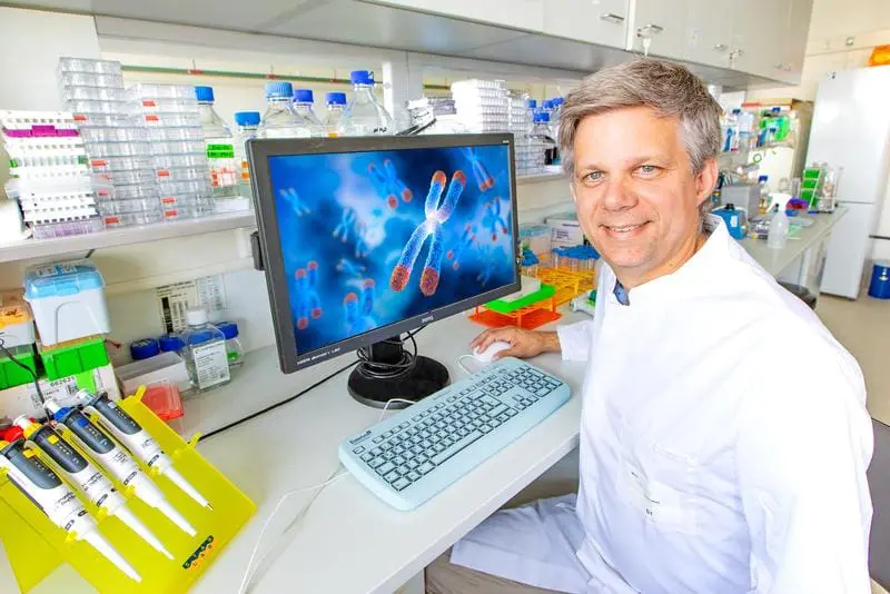 Professor Dölken im Institut für Virologie der Medizinischen Hochschule Hannover (MHH). Auf dem Bildschirm ist die Abbildung eines Chromosoms zu sehen mit dem Zentromer in der Mitte. | Copyright: Copyright für das Foto: Karin Kaiser/MHH. Copyright für die Abbildung auf dem Bildschirm: iStock/peterschreiber.media