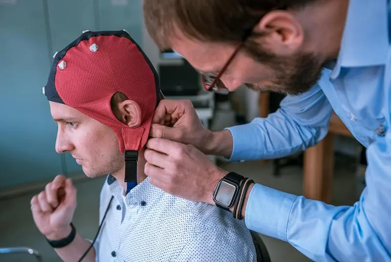Prof. Patrique Fiedler passt einem Probanden eine Haube zur Messung der Gehirnaktivität anu | Quelle: Dino Junski | Copyright: TU Ilmenau 