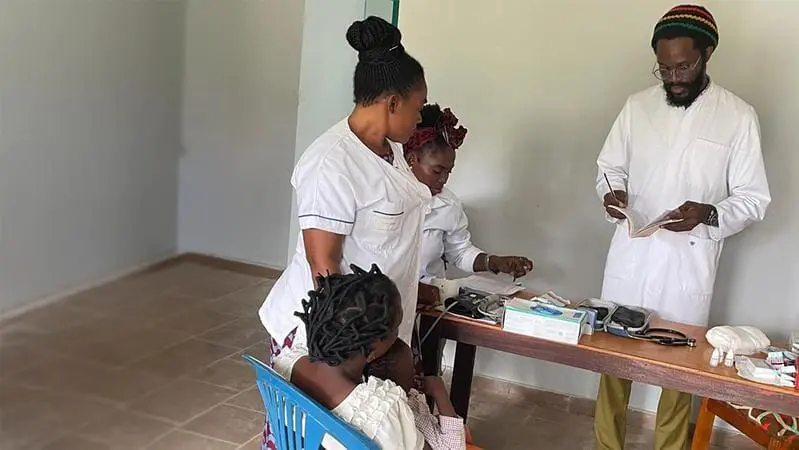 Behandlung einer Patientin am CERMEL-Satellitenstandort Mighoma im Rahmen der klinischen SPAP-Studie in Gabun. Zu sehen sind die Krankenschwester Merleye Nongou (stehend), die Datenerfasserin Naomie Badinga (sitzend), sowie Dr. Alex Hounmenou Zinsou. | Copyright: Ghyslain Mombo-Ngoma