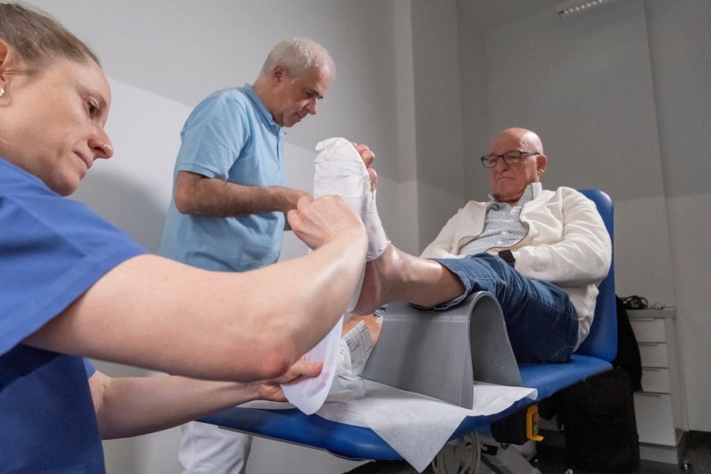 Nursing scientist Mira Mertens and diabetologist Dr. Dirk Hochlehnert adapt the newly developed AI-supported wound dressing to a patient with diabetic foot syndrome. With the help of a built-in sensor, this detects when the pressure on a wound becomes too great and sends an alarm to the patient's smartwatch. The wound is also measured digitally, making the work of caregivers easier. The innovation was developed as part of the EPWUF-KI project at the Niederrhein University of Applied Sciences in Krefeld and at the Center for Diabetology, Endoscopy and Wound Healing in Cologne. Image rights: Bosch Health Campus Photographer: David Klammer